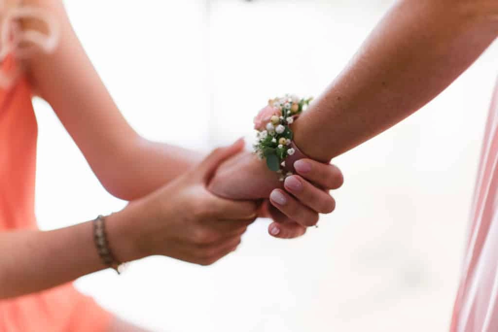 Hochzeitsgast bekommt ein Blumenarmband angelegt.