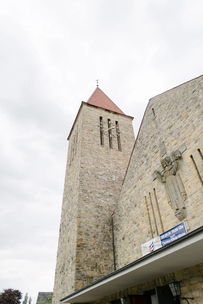 Steinerner Kirchturm mit rotem Dach.