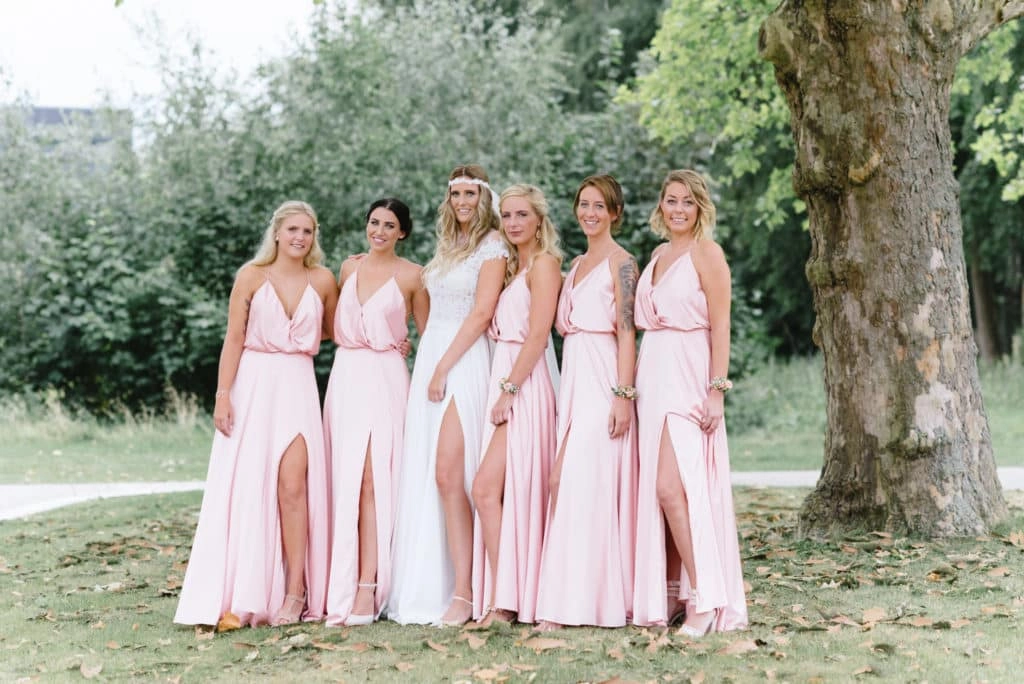 Braut posiert mit Gästen in rosa Kleidern.