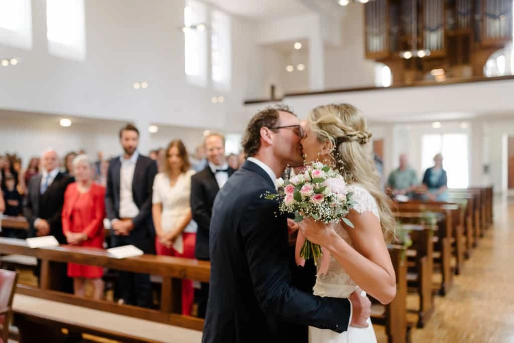Braut umarmt den Bräutigam im Kirchenschiff.