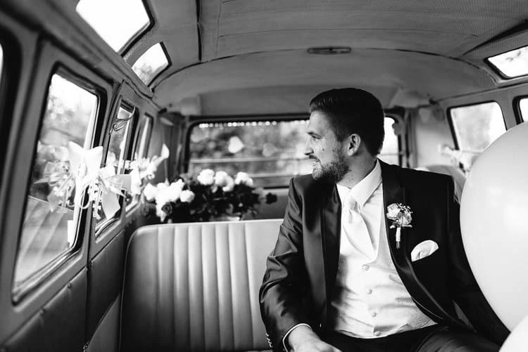 Bräutigam schaut aus dem Oldtimerbus, in Schwarz-Weiß.
