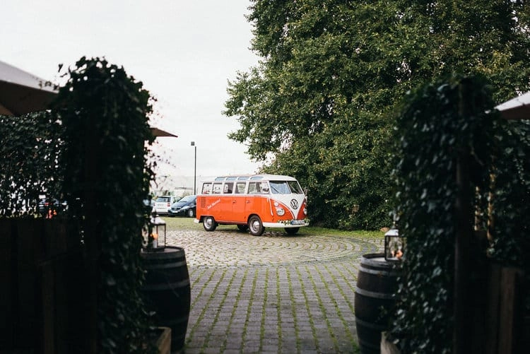 Orangefarbener Oldtimerbus vor der Hofeinfahrt.