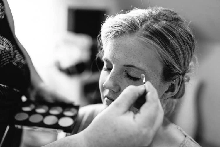 Augen-Make-up der Braut wird aufgetragen, in Schwarz-Weiß.