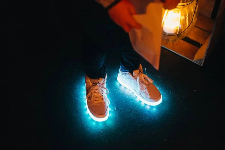 Schuhe mit blau leuchtenden Sohlen auf der Tanzfläche.
