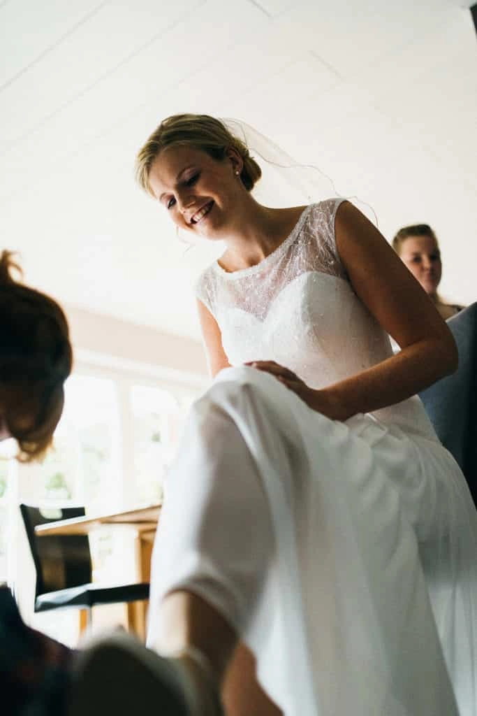 Braut bekommt Hilfe beim Anziehen des Kleids.