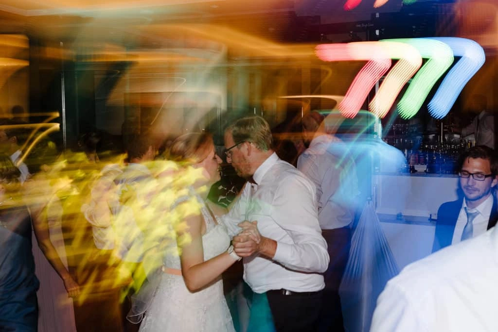 Brautpaar tanzt bei buntem Partylicht.