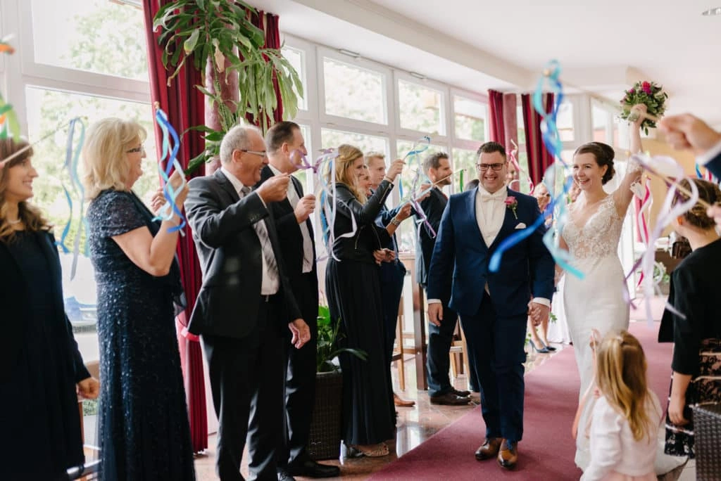 Brautpaar zieht zwischen den Gästen in den Festsaal ein.