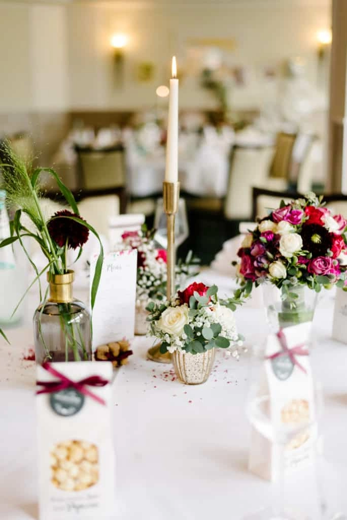 Hochzeitstisch mit rosa-violetten Blumen und Kerzen.