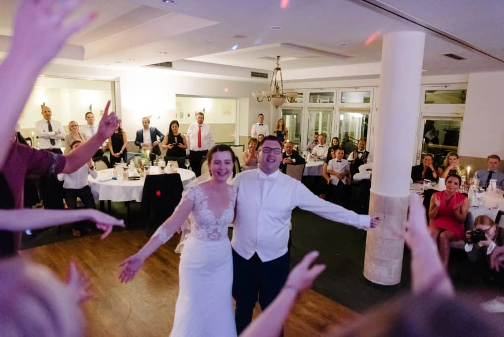 Brautpaar wird im Festsaal mit bunten Bändern begrüßt.