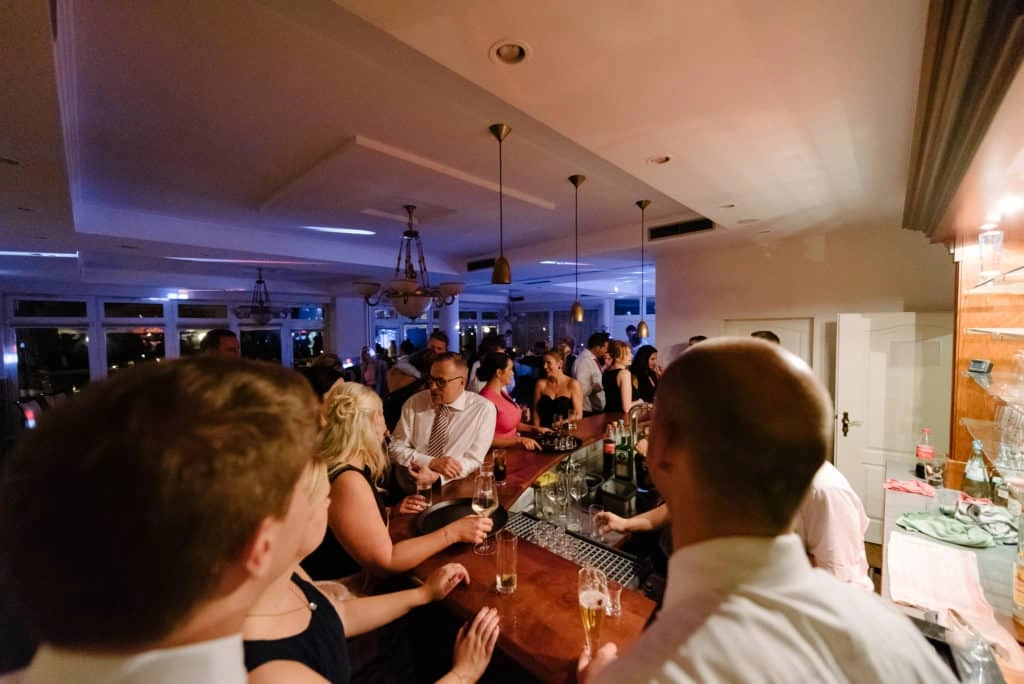 Hochzeitsgäste unterhalten sich an der Bar im Festsaal.