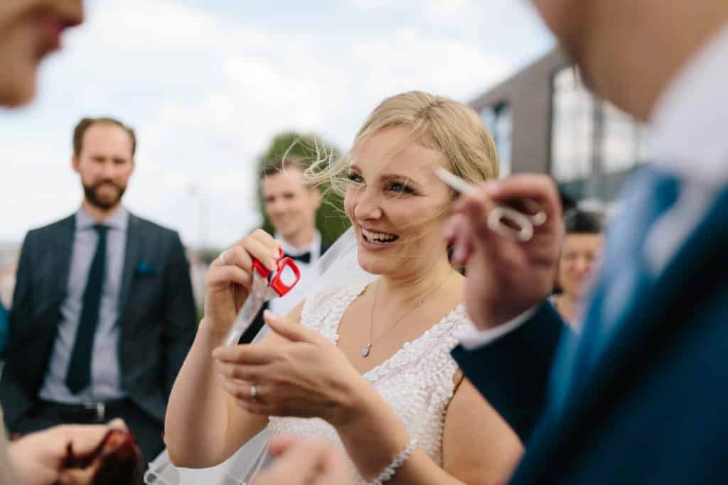 Die Braut lacht beim Empfang im Freien neben dem Bräutigam.
