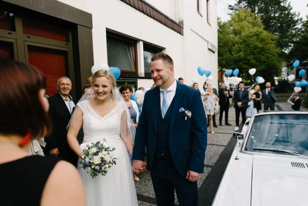 Braut und Bräutigam verlassen Hand in Hand das Traugebäude.