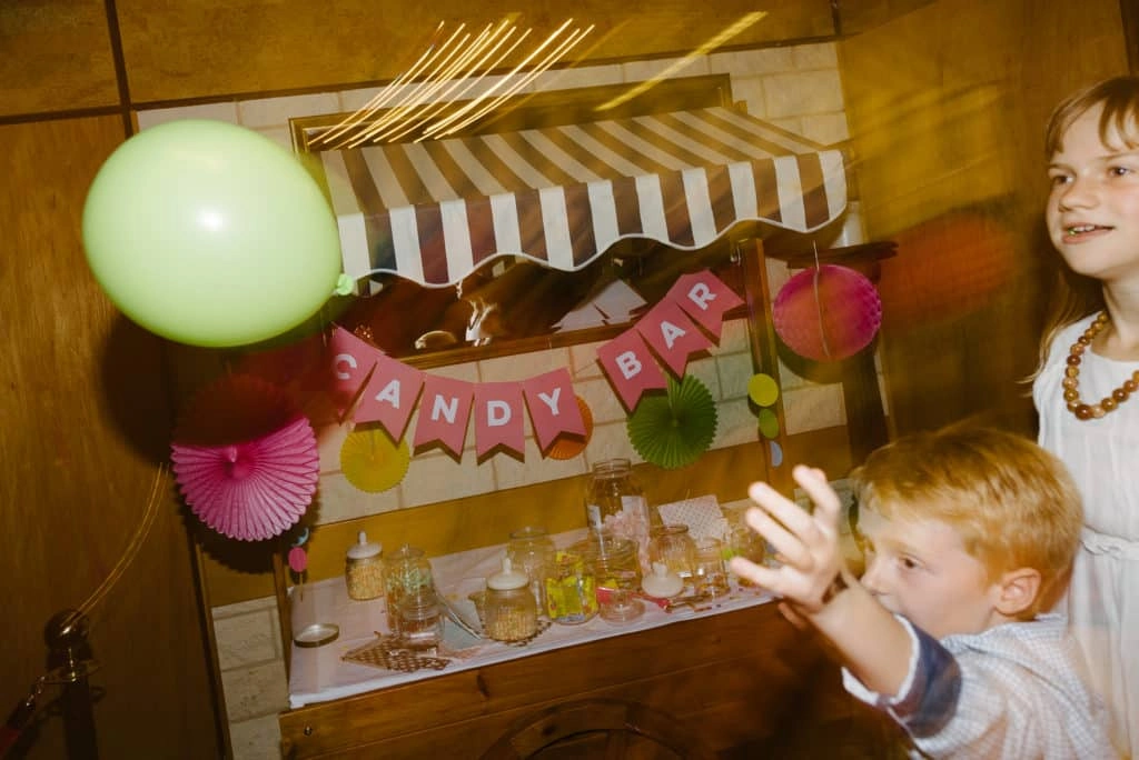 Kinder spielen mit Ballons neben einer Candybar.