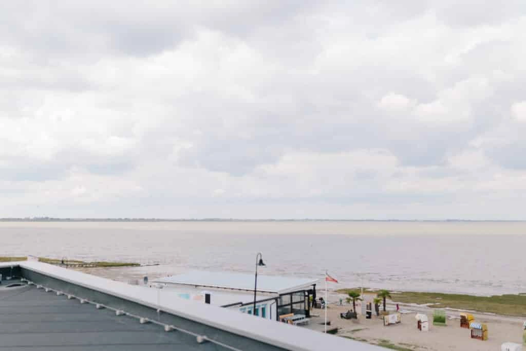 Blick über die Küste bei Dangast mit Strand, Meer und bedecktem Himmel.