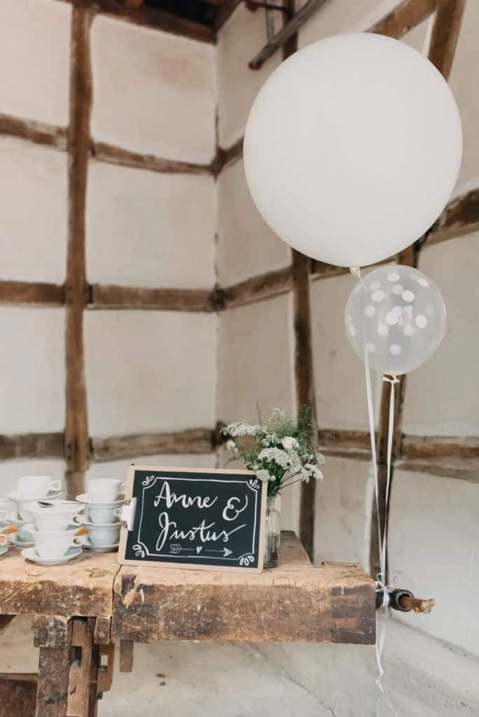 Luftballons und kleine Tafel vor einer Fachwerkwand.