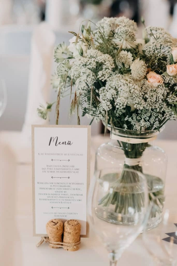 Menükarte und Blumen auf der Hochzeitstafel.