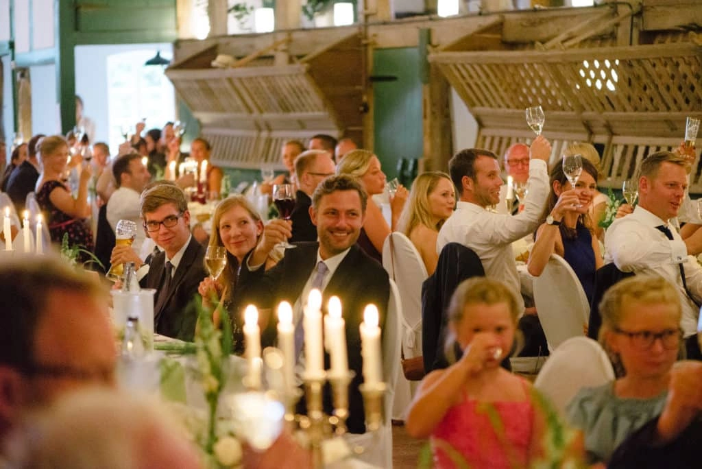 Gäste an den festlich gedeckten Hochzeitstischen im Fachwerksaal.