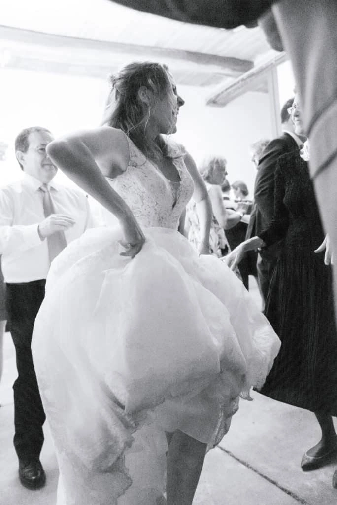 Braut hebt beim Tanzen den Rock ihres Hochzeitskleids an.
