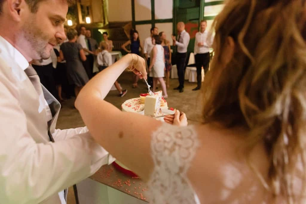 Braut und Bräutigam probieren gemeinsam die Hochzeitstorte im Festsaal.