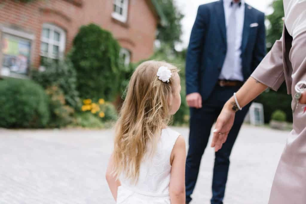 Kind mit Haarschmuck vor den Hochzeitsgästen.