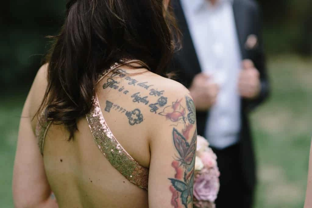 Detail des glitzernden Brautkleids und der Tätowierungen.