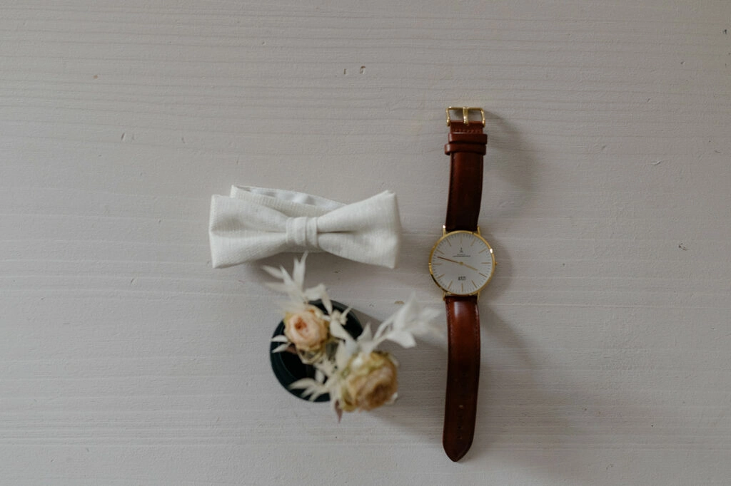 Weiße Fliege, Armbanduhr und Blumenanstecker für den Bräutigam.
