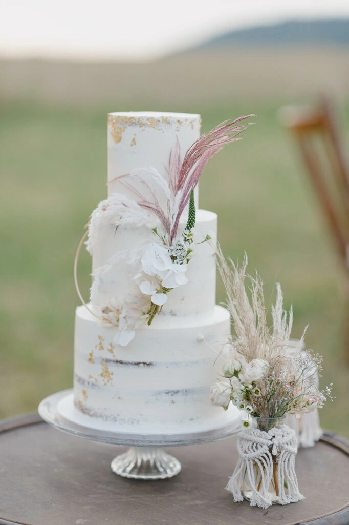 Dreistöckige Hochzeitstorte auf einer Holzscheibe im Freien.