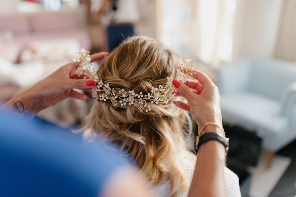 Blumenschmuck wird in der Hochzeitsfrisur befestigt.