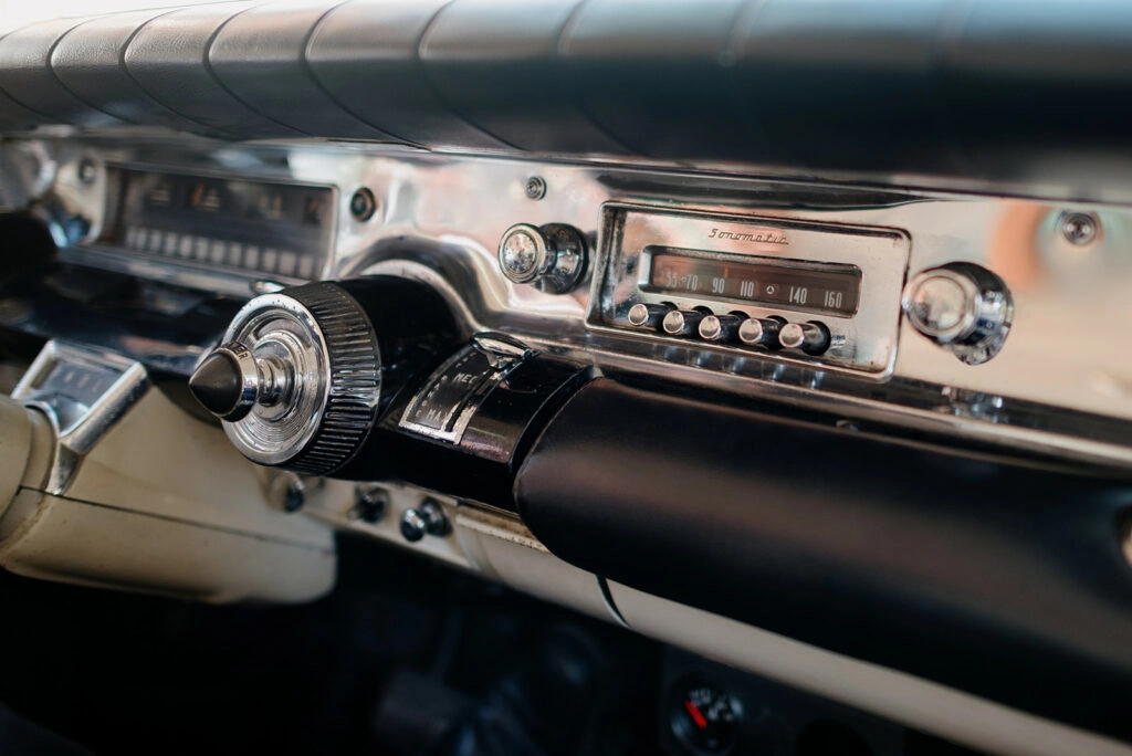 Armaturenbrett eines Oldtimers mit Radio und Chromdetails.