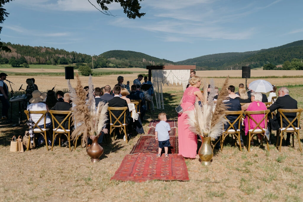 Hochzeitsgäste warten bei einer freien Trauung auf dem Feld.