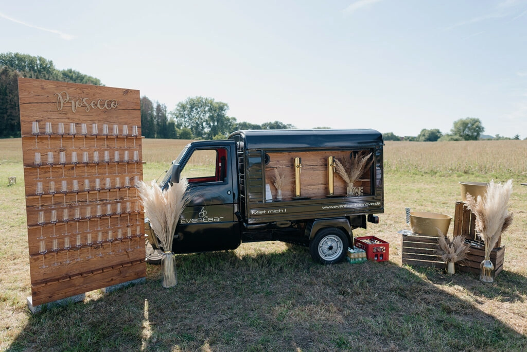 Mobiler Ausschankwagen und rustikale Dekoration am Feldrand.