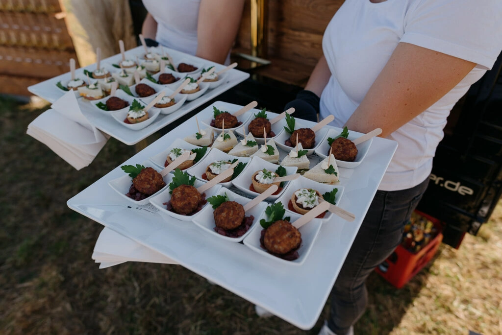 Eine Servicekraft trägt zwei Tabletts mit Fingerfood.