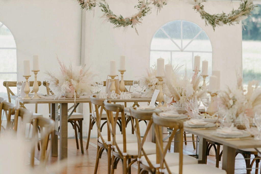 Gedeckte Hochzeitstafel mit Holzstühlen und Trockenblumen.
