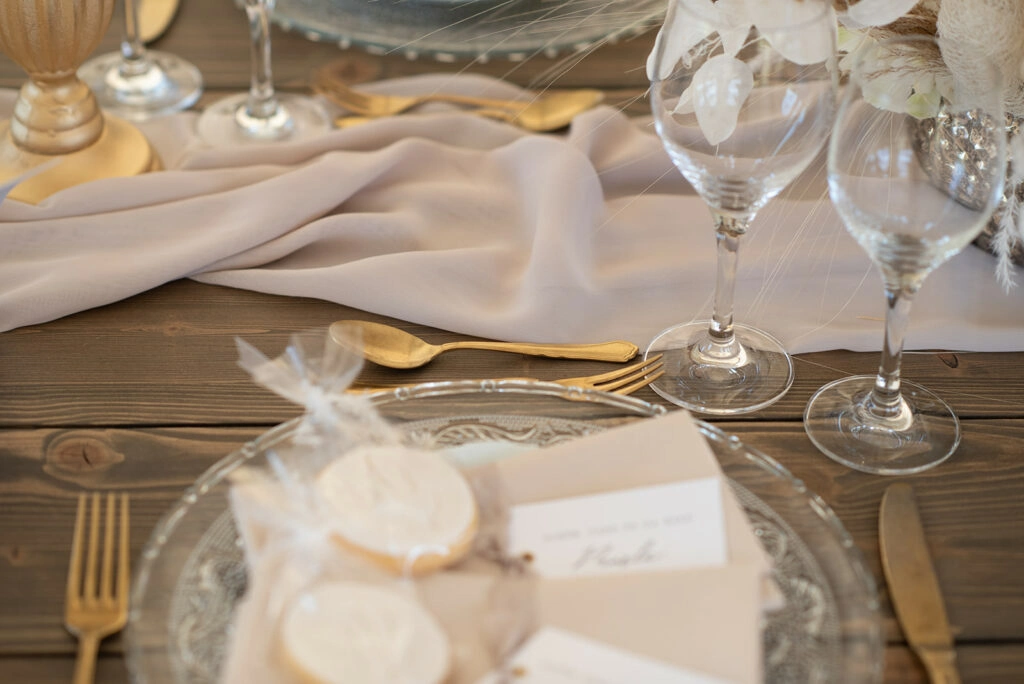 Gedeckter Hochzeitstisch mit goldfarbenem Besteck und Stoffservietten.