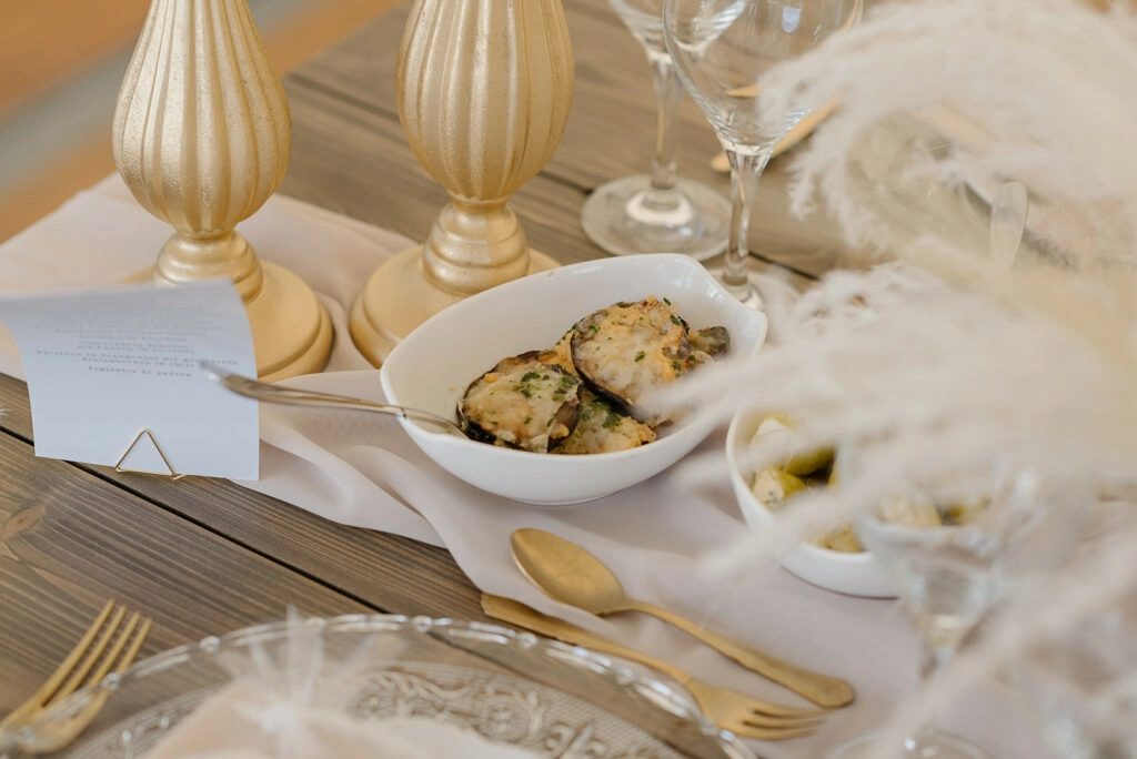 Speisen, goldfarbenes Besteck und Kelche auf der Hochzeitstafel.
