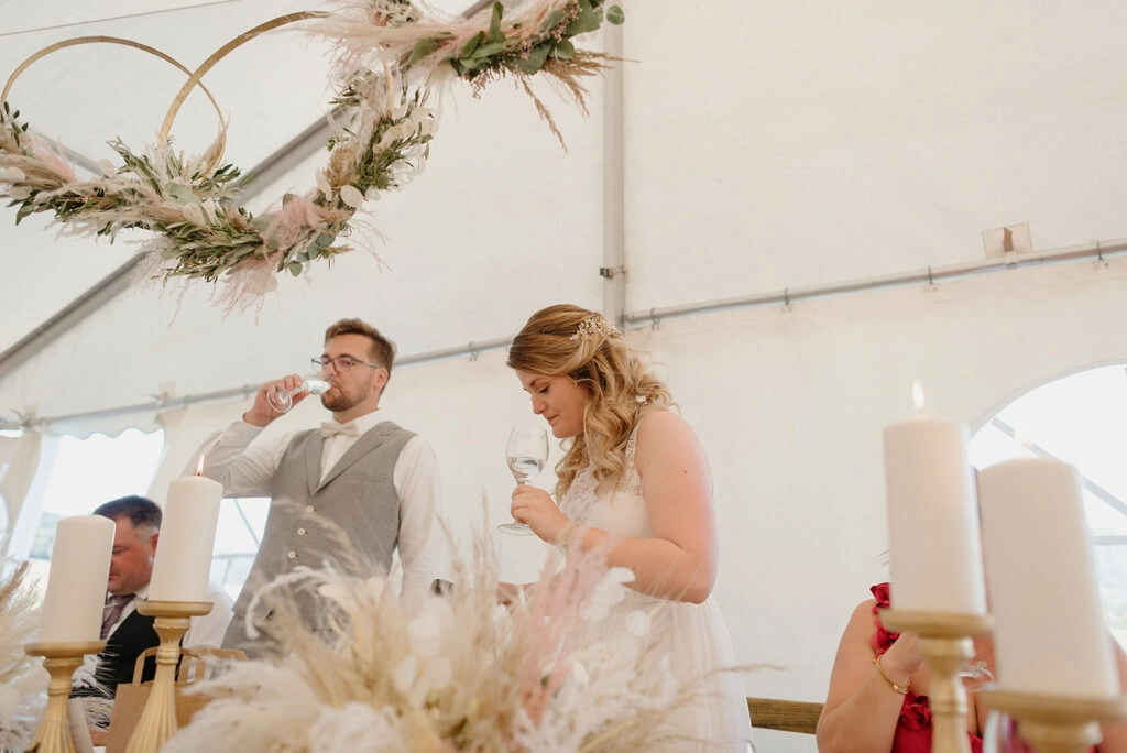 Das Brautpaar steht an seiner Hochzeitstafel im Festzelt.