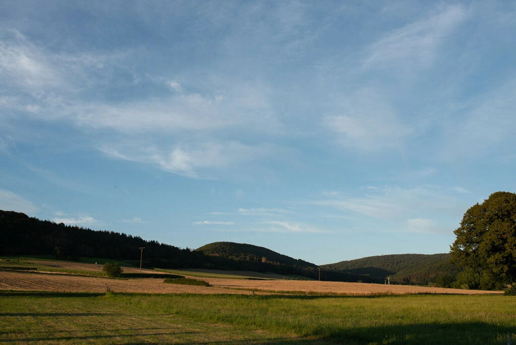 Weite Felder und Hügel unter blauem Himmel.