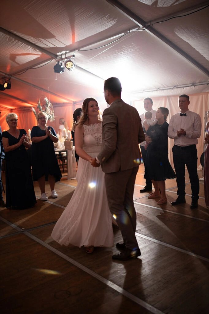 Brautpaar beim Hochzeitstanz im warm beleuchteten Festzelt.