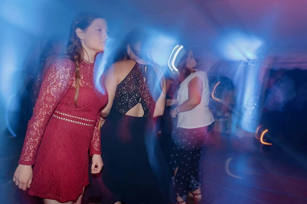 Hochzeitsgäste tanzen im blauen Partylicht.
