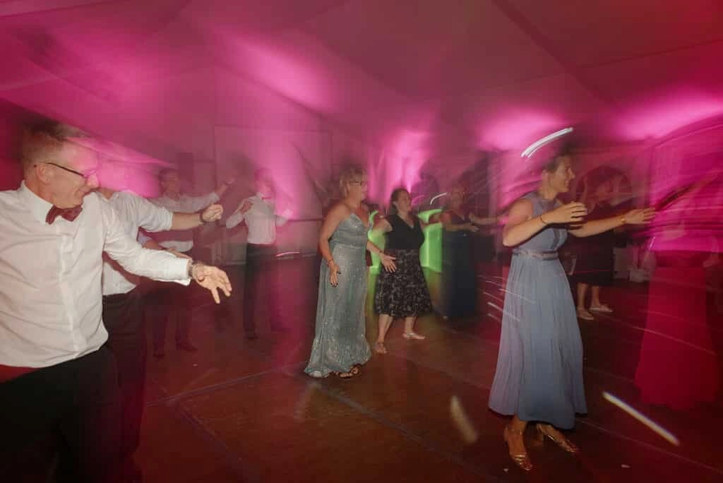 Tanzende Hochzeitsgäste im pink beleuchteten Festzelt.