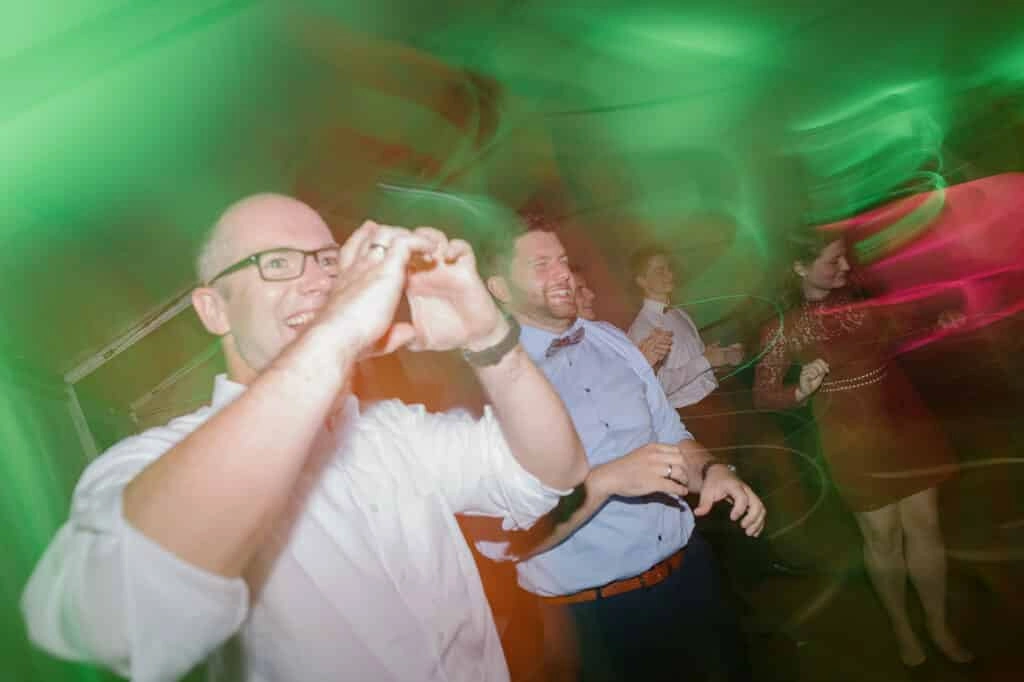 Hochzeitsgast trinkt auf der Tanzfläche im grünen Partylicht.