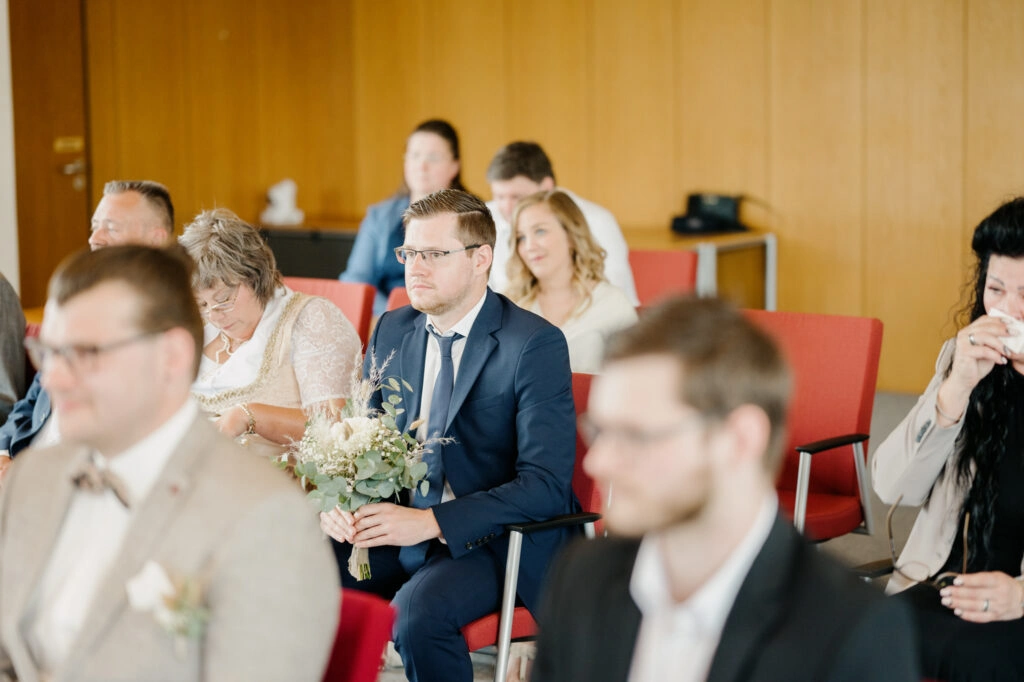 Gäste verfolgen die Trauung hinter dem Brautpaar.