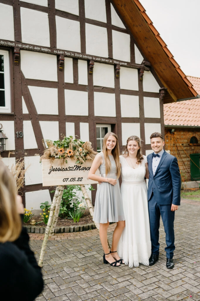 Zwei Hochzeitsgäste stehen vor einem Fachwerkhaus.
