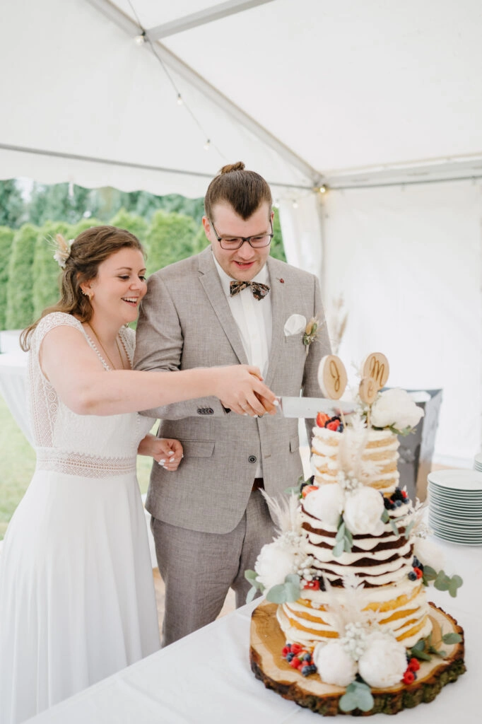 Brautpaar schneidet gemeinsam die Hochzeitstorte an.