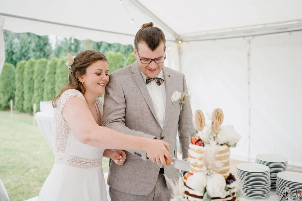Brautpaar schneidet die Hochzeitstorte im Festzelt an.