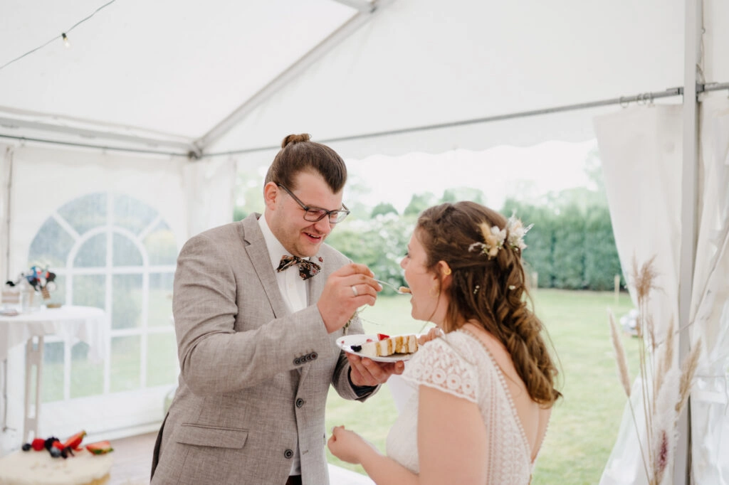 Bräutigam probiert die Hochzeitstorte neben der Braut.