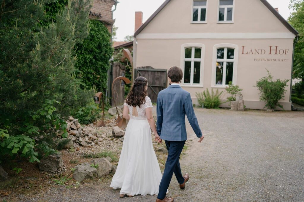 Brautpaar spaziert Hand in Hand zum Landhof.