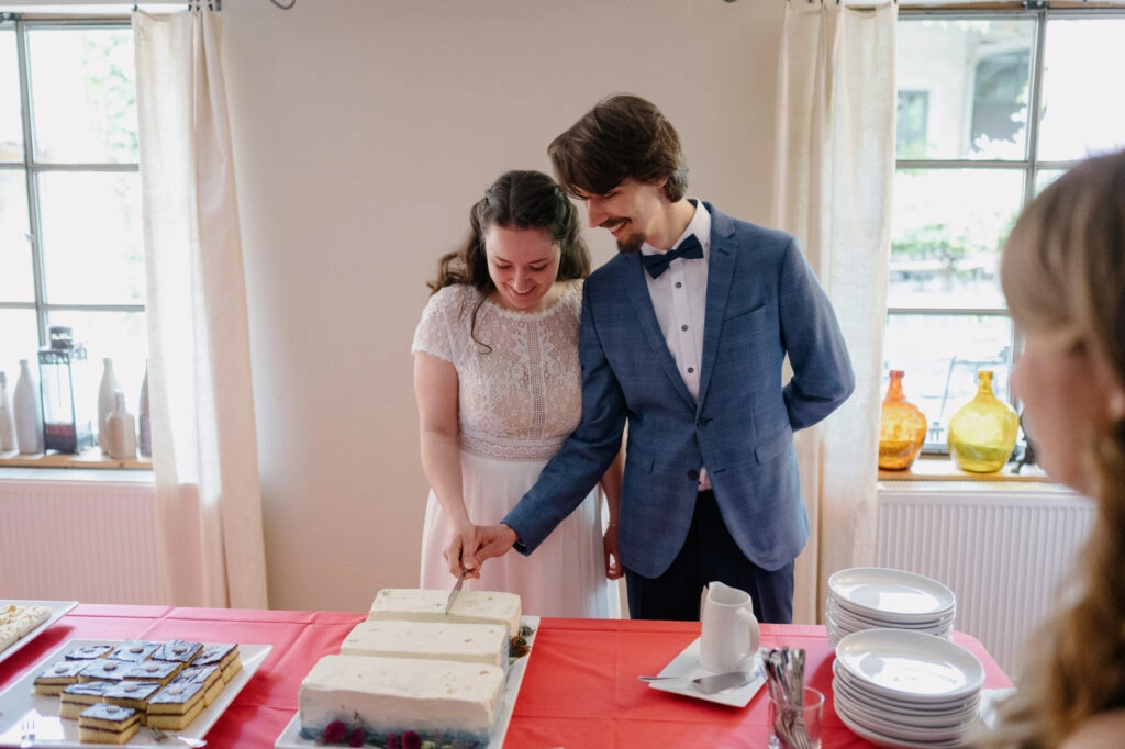 Brautpaar schneidet gemeinsam die Hochzeitstorte an.