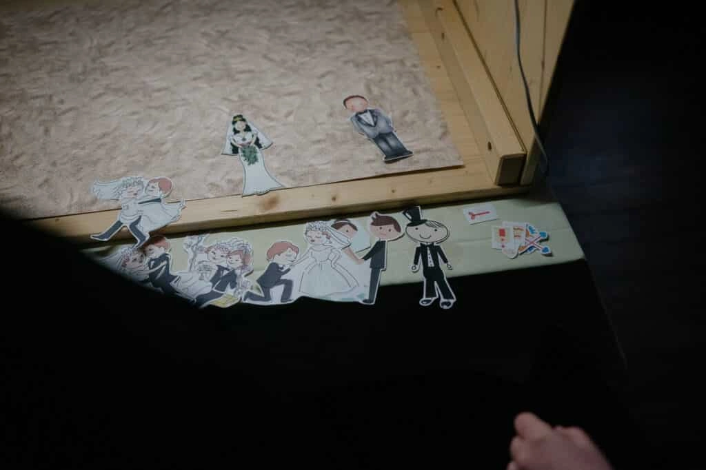 Ausgeschnittene Figuren liegen vor einer gestalteten Holztafel.