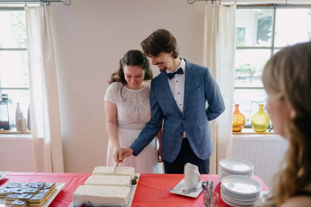 Brautpaar schneidet gemeinsam eine rechteckige Hochzeitstorte an.
